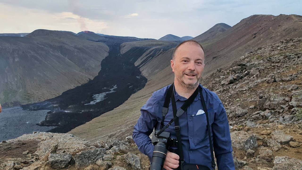 Portrait de Sylvain Bellier dans un paysage volcanique, un appareil photo autour du cou